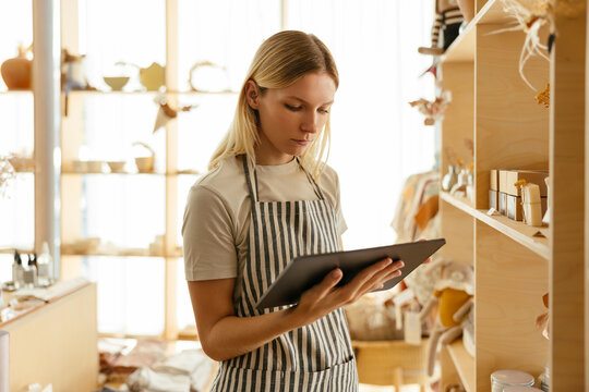 Owner wearing apron taking inventory on tablet PC at store