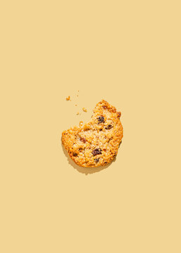 Raisin cookie with missing bite against yellow background