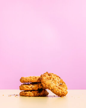 Raisin cookies stacked against pink colored background