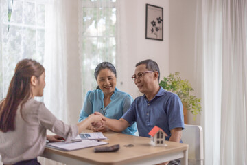 Obraz premium Elderly couples satisfying retirement home purchase with contract and key handover from a saleswoman