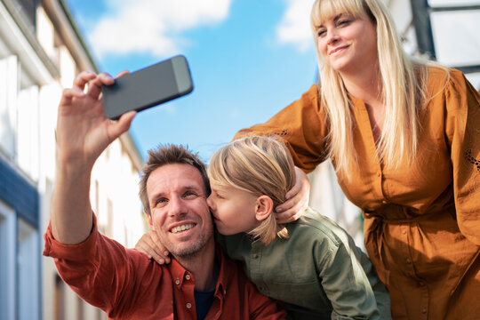 Smiling father taking selfie through smart phone with family
