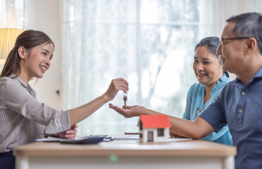 Elderly couples satisfying retirement home purchase with contract and key handover from a saleswoman