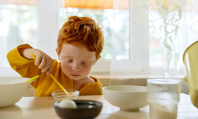 Boy mixing sugar in bowl on dining table at home