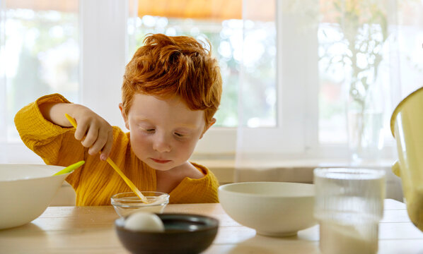 Boy mixing sugar in bowl on dining table at home