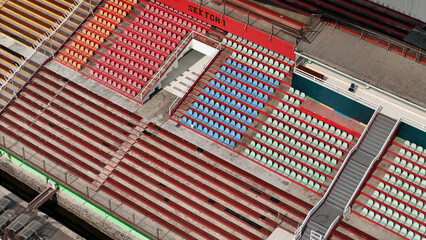 A fragment of the grandstand of an sports stadium with multi-colored seats. Empty seats