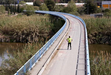 Man standing with arm akimbo on bridge