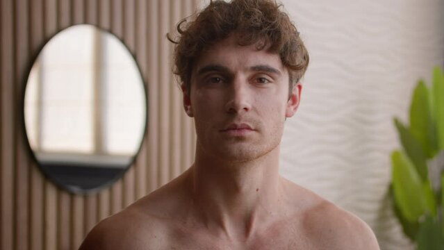 Close up head shot portrait young adult millennial Caucasian handsome European male naked guy shirtless appearance man serious calm posing in bathroom procedure healthy bearded model looking at camera