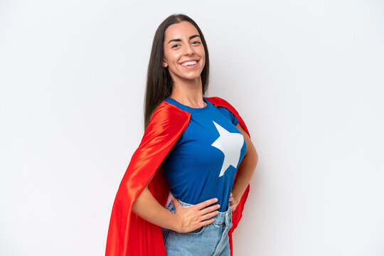 Young caucasian woman isolated on white background in superhero costume and doingposing with arms at hip and smiling