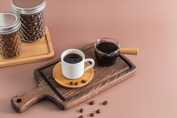 A small coffee cup on a wooden saucer and a coffee pot with freshly brewed coffee stand on a...