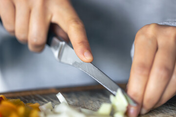 A woman cuts vegetables on a cutting board.