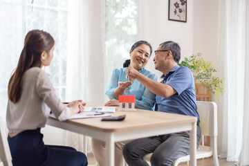 Elderly couples satisfying retirement home purchase with contract and key handover from a saleswoman