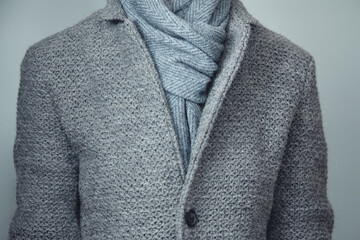 Gray knitted jacket and blue scarf close-up. Winter, autumn warm woolen clothes.