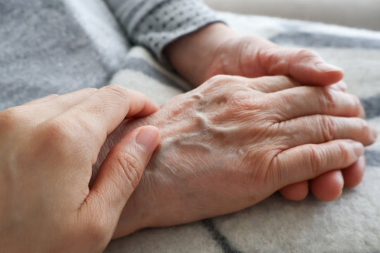 高齢女性の手を握る女性の手
