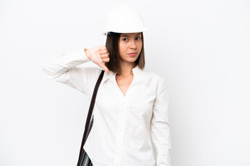 Young architect woman with helmet and holding blueprints isolated on white background showing thumb down with negative expression