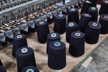 Spools of black thread on the spinning machine in a textile factory.