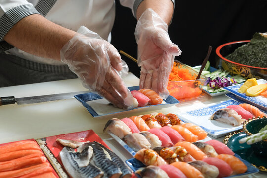 A skilled chef prepare a variety of sushi on a table. Mixing flavor, texture, and color, the chef creates culinary art. Each sushi is a precise masterpiece, showcasing their expertise and dedication.