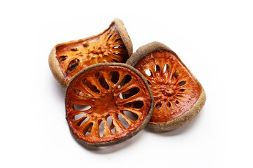Dried bael fruit slices on white background.