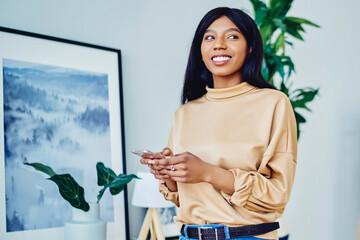 smiling dark skinned hipster girl holding smartphone making booking spending time at flat