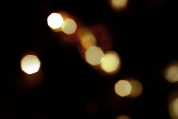 Obraz premium festive New Year's bokeh of warm yellow color, blurred on a dark background