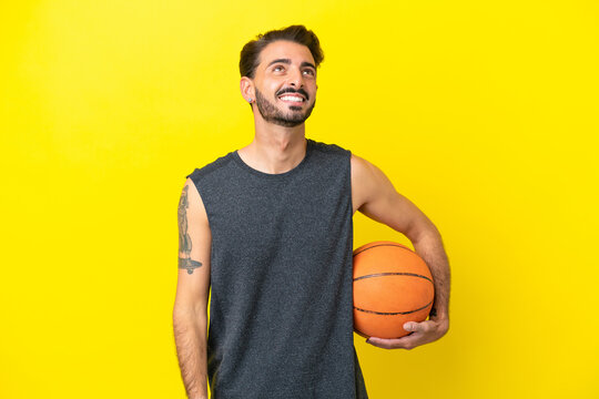 Handsome young basketball player man isolated on yellow background thinking an idea while looking up