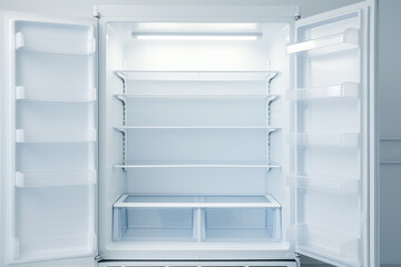 An open empty fridge in a kitchen. Hungry and food price concept - obrazy, fototapety, plakaty