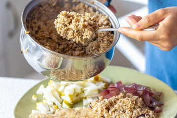 A woman prepares oatmeal with fruits, close-up.