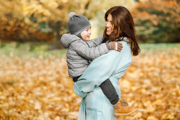 Mother and son in autumn park carrying flowers.