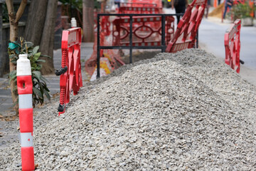 Street road making construction with gravel and barrier inside city road. Gravel for repairing road.