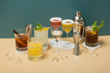Composition with alcoholic cocktails and bar tools on podiums on colored background.