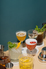 Composition with alcoholic cocktails and bar tools on podiums on colored background. Copy space.