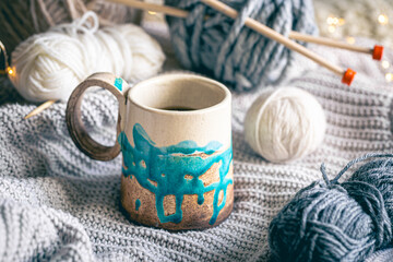 Cozy composition with a cup of coffee, threads and a knitted element.