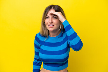 Young Rumanian woman isolated on yellow background looking far away with hand to look something