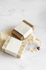 Beige handmade soap bars with blank label on soap saver bag close up, mockup