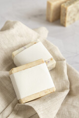 Beige handmade soap bars with blank label on linen towel close up, mockup
