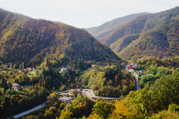 Fototapeta na wymiar Panoramic view from above, from the throne to the valley in the mountains. A small village in the Alps. Colored houses, tiled roofs, a road and a river. Europe