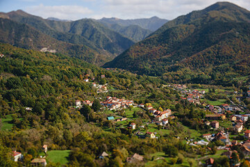 Naklejka na ściany i meble Panoramic view from above, from the throne to the valley in the mountains. A small village in the Alps. Colored houses, tiled roofs, a road and a river. Europe. Italy