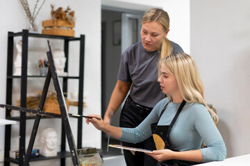 a young female student artist learning how to draw with her teacher