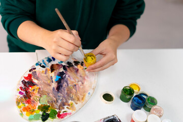 artist holding a small acrylic gouache paint in the workshop