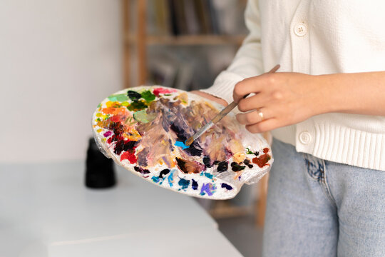 artist holding a brush and a palette to mix the new color