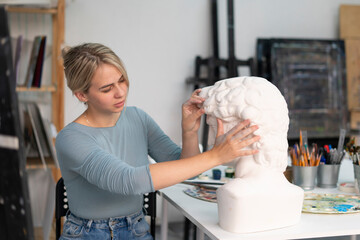 young female sculptor making gypsum sculpture