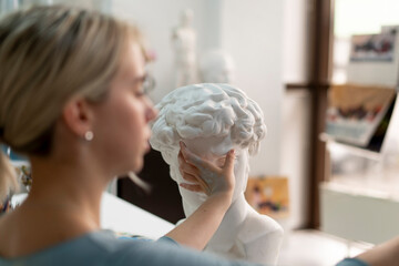 young female sculptor making gypsum sculpture