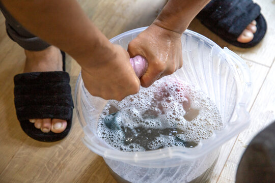 Woman wring out the rag in a bucket of water at home without gloves. Hands close up.