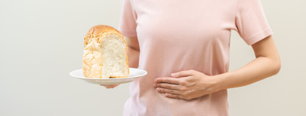 Gluten allergy woman hand holding, refusing to eat white loaf slice on plate in breakfast food meal at home, girl having a stomach ache. Gluten intolerant and Gluten free diet, isolated on background. - obrazy, fototapety, plakaty