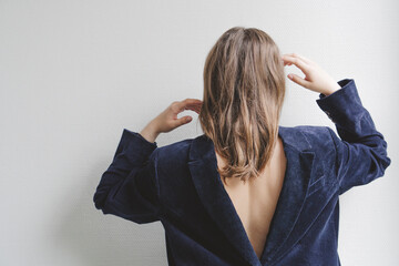 Brunette teenage girl wearing navy blue blazer backwards in front of wall