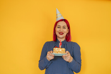 Smiling woman with dyed hair holding birthday cake