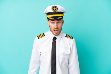 Airplane caucasian pilot isolated on blue background with surprise facial expression