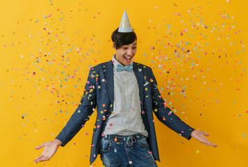 Happy young man with party hat enjoying amidst falling confetti