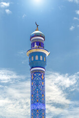 Minaret of a mosque with oriental ornaments and Arabic script in the old Mutrah market of Muscat. Sultanate of Oman