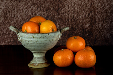 Pottery Chalice Bowl with Satsuma Oranges on a Polished Wooden Table Top - 670033953