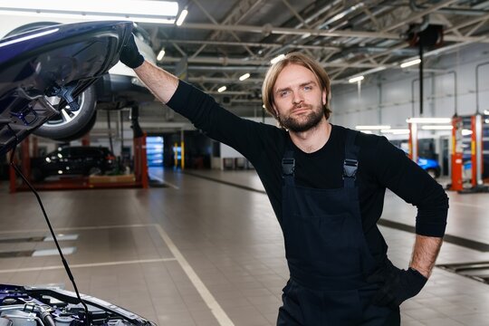 Portrait of a successful car mechanic next to a car against the background of a modern car service